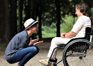 Person speaking to someone in a wheelchair.