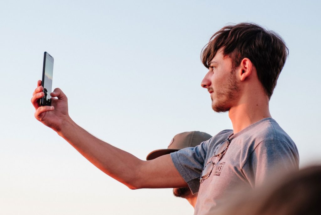 Man holding out phone in front of himself to take a picture