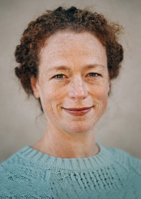 Middle aged woman with curly red hair smiling.