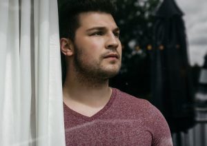 Man looking out window of home.