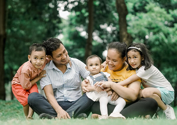 A seated family group of five on green grass.