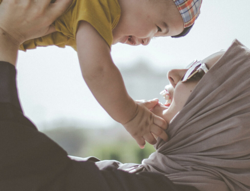 Happy mother holding and playing with her laughing child.