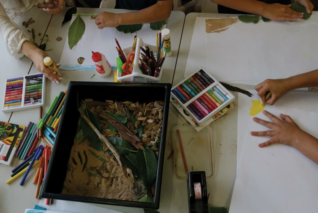 Children creating art, colouring and pasting on a desk.