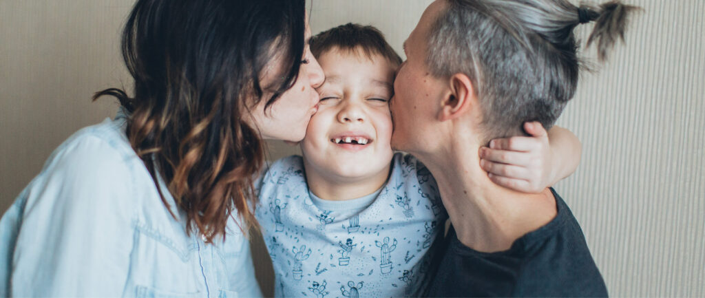 Parents kissing the cheeks of their son.