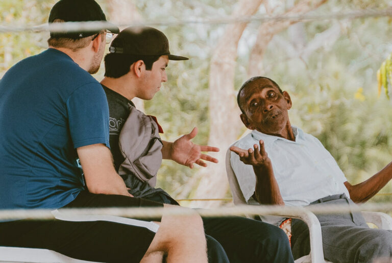 Two young men talking to an older an in public space.