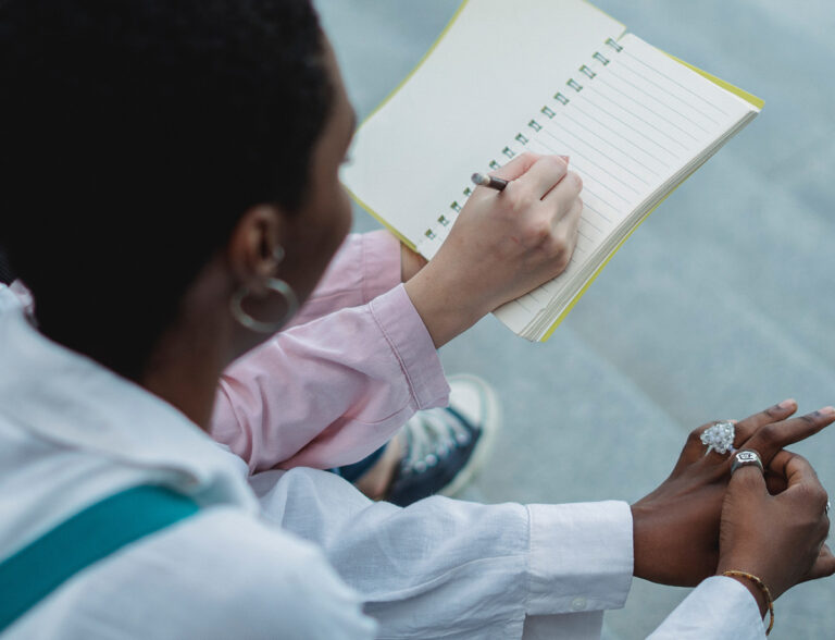 Two people looking at a worksheet and diary.