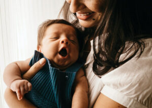 Mother holding her yawning newborn child.