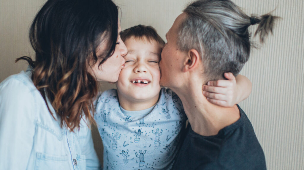 Parents kissing both sides of childs cheeks.