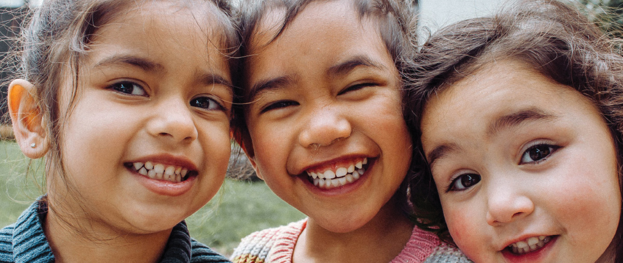 Three kids smiling with heads together.