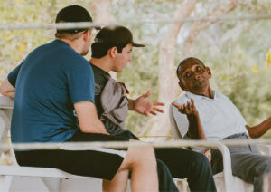 Older man talking with two younger men in public space.