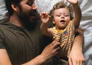 Father playing with son on bed.