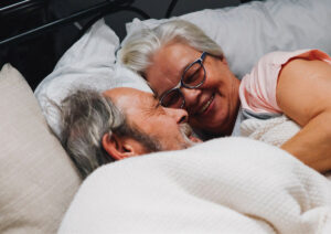 An old couple laughing together in bed.