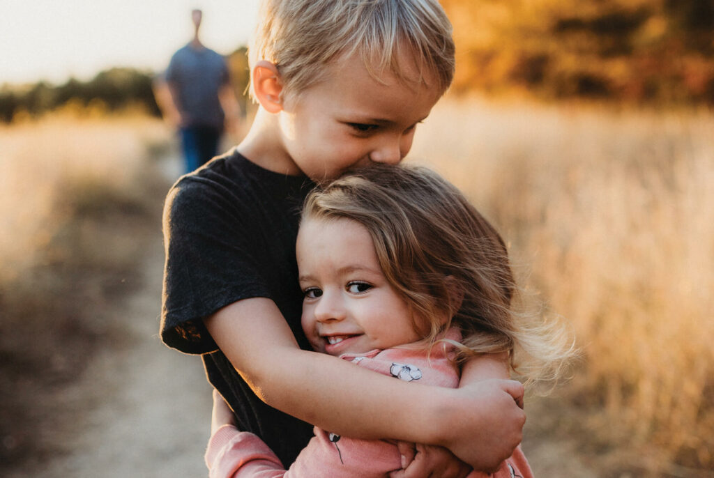 Two small children happily hugging at sunset.