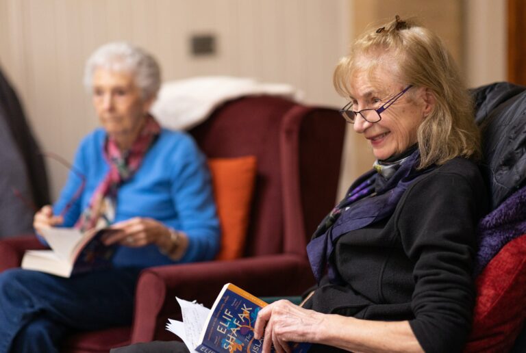 Two elderly women sitting reading.