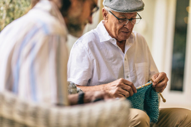 Elderly man knitting.