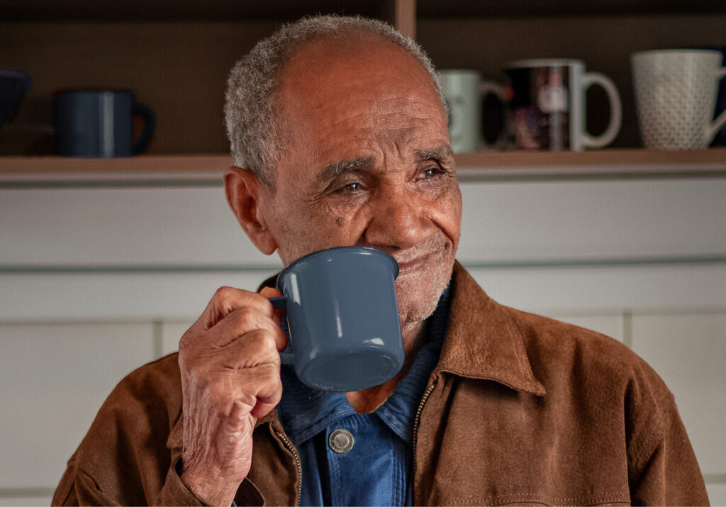 Elderly man drinking a cup of coffee at home.