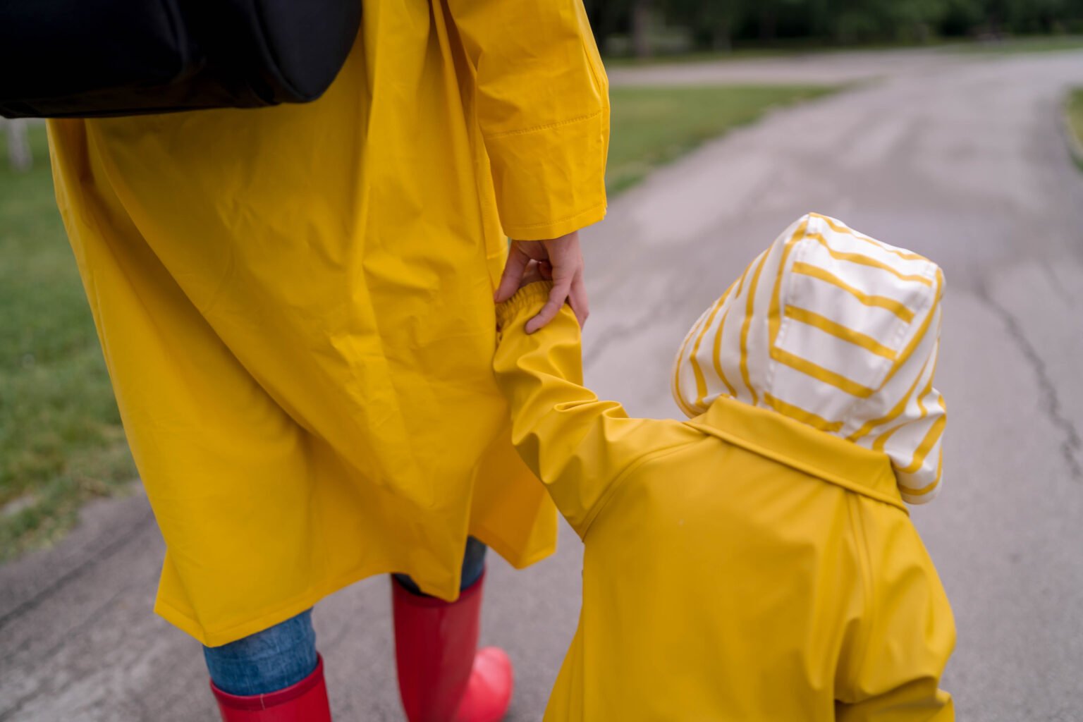 A mother and young child walking hand in hand through a park